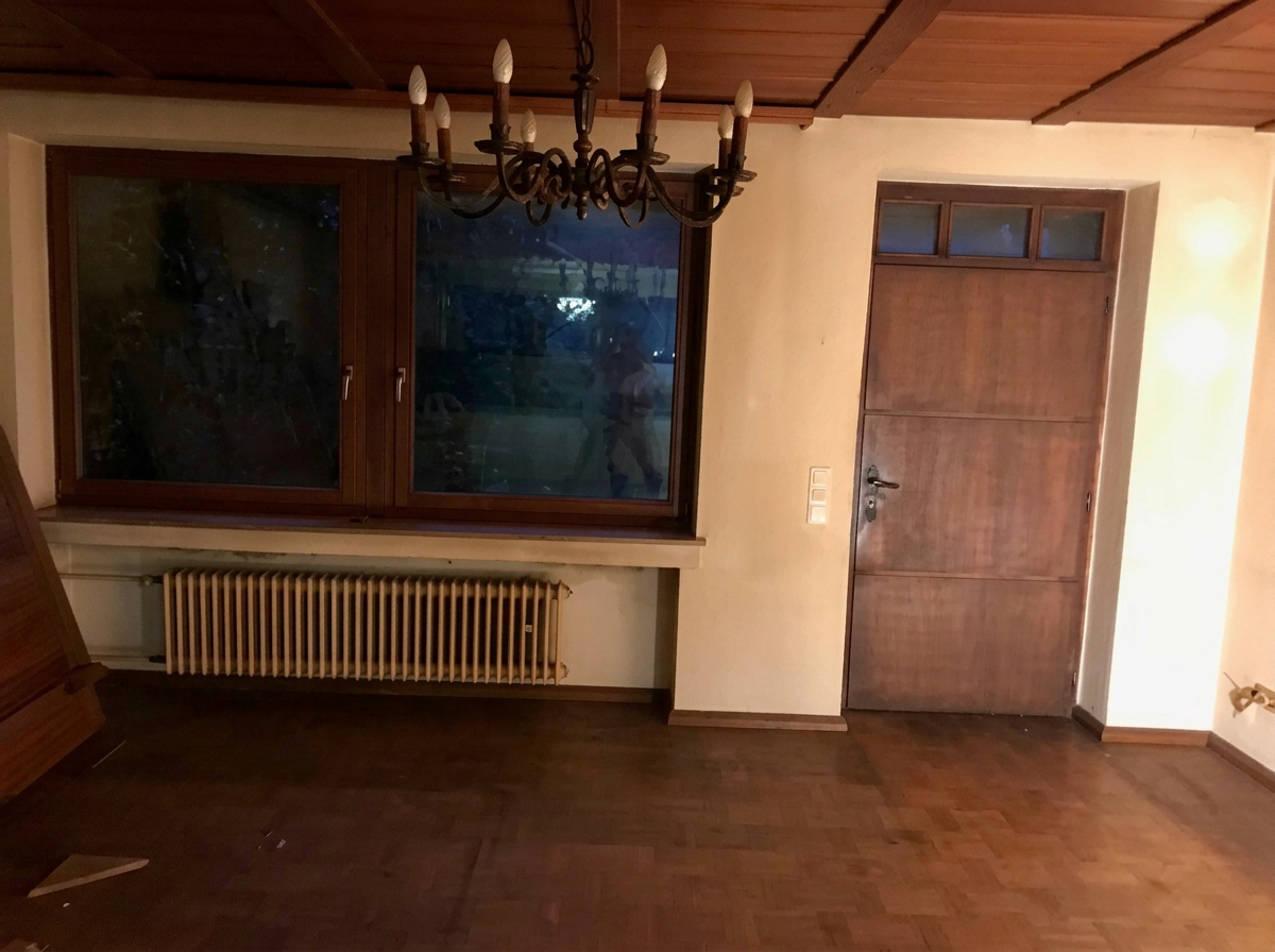 Wohnbereich vor der Sanierung mit dunklen Holzflächen und altem Kronleuchter